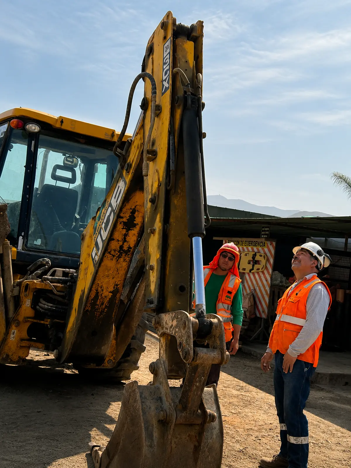 Técnicos de JC Electrohidráulicos revisando el brazo de una retroexcavadora JCB junto al operador